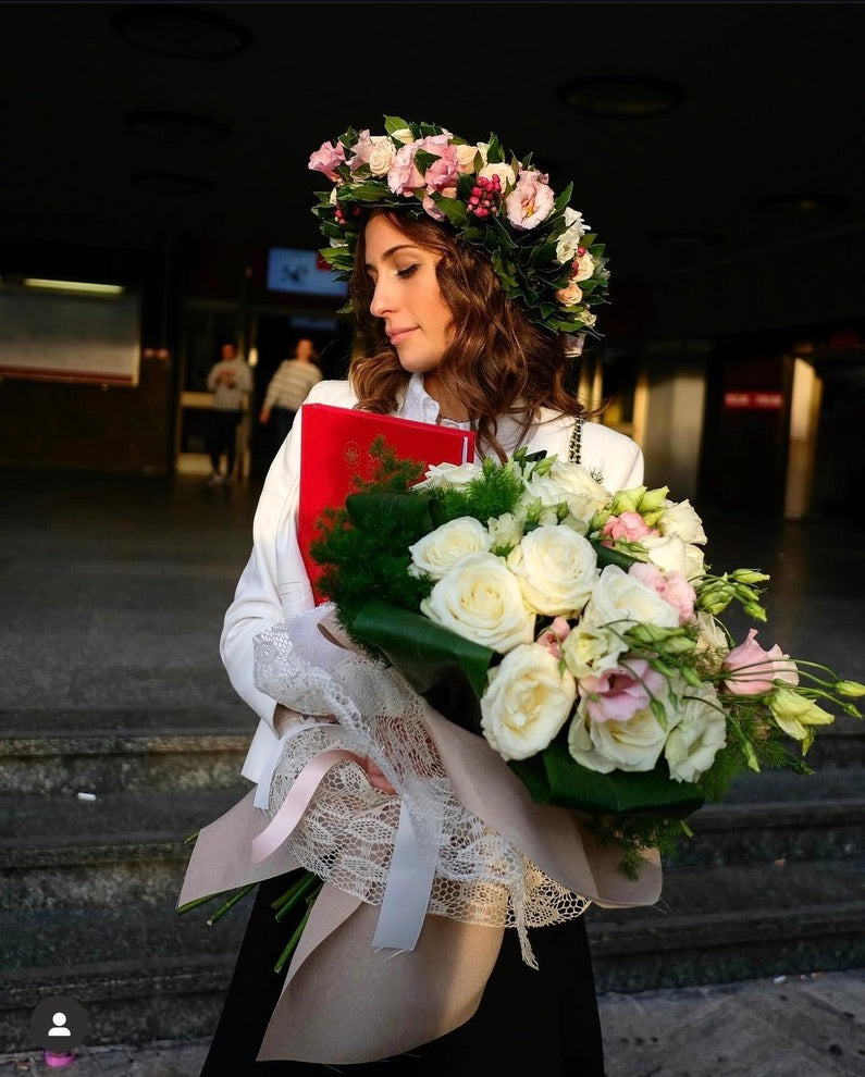 Laureata con corona d’alloro artigianale decorata con fiori rosa e bianchi