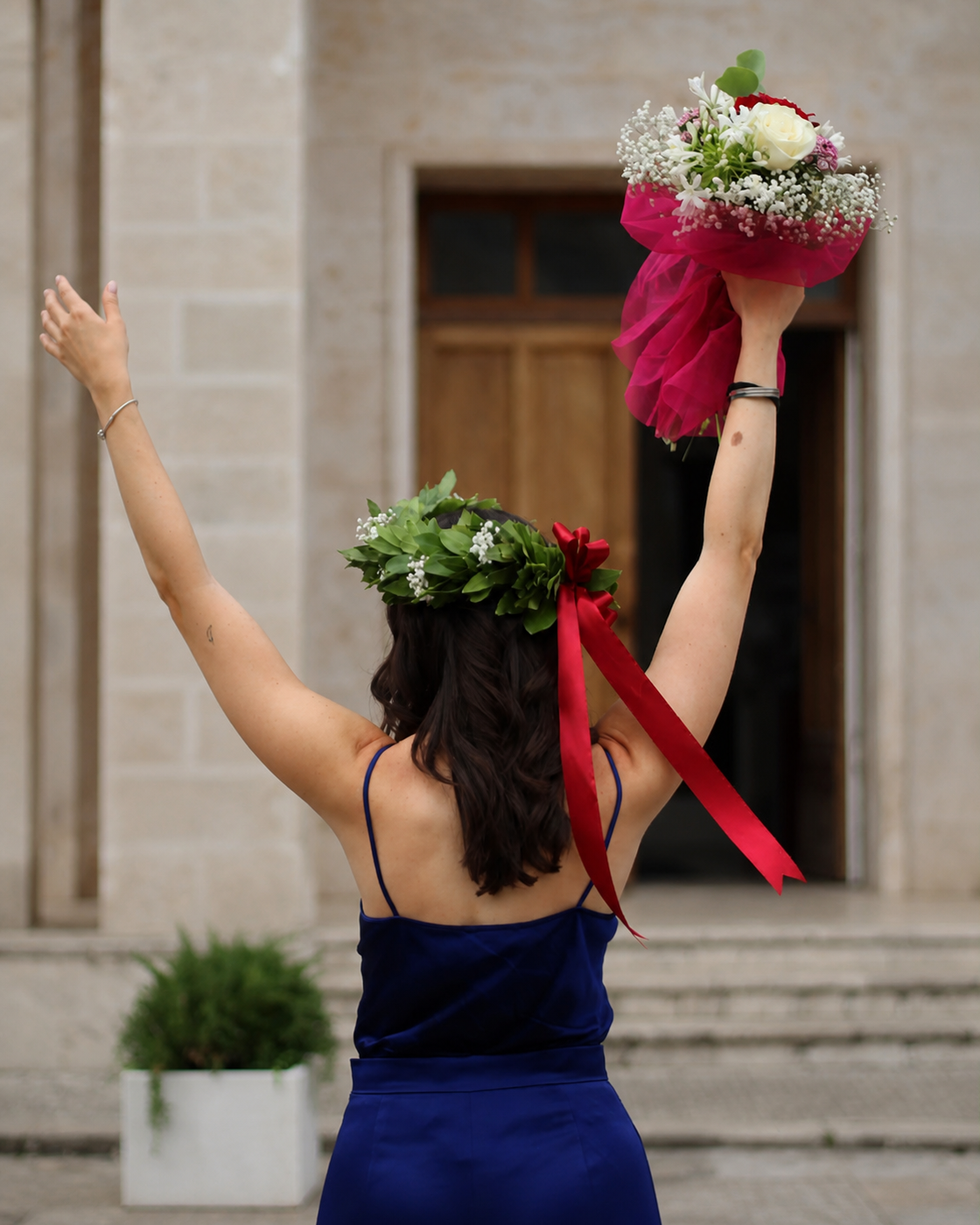 Laureata di spalle con corona d’alloro e bouquet alzato nel giorno della proclamazione
